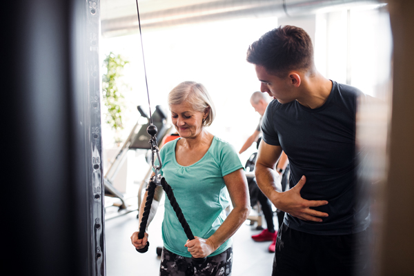 older woman with trainer in the gym